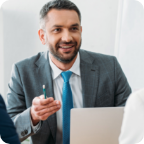 A businessperson dressed in a suit is animated as he speaks with a client.